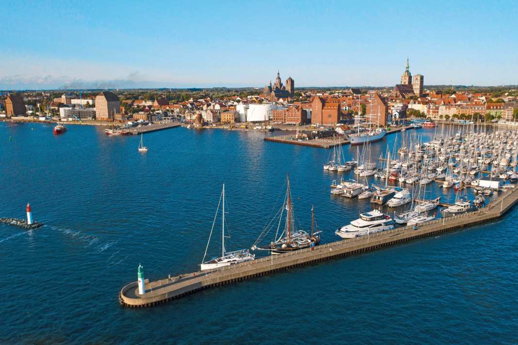 Der Stadthafen von Stralsund mit der Citymarina, den markanten Speichern und der Altstadt dahinter. Die weiße Fassade gehört dem Meeresmuseum Ozeaneum
