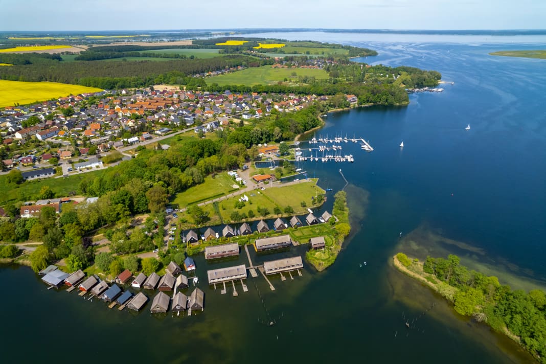 Blick vom Röbeler Binnensee über Bootshäuser und die Stege der Marina Röbel mit der Müritz im Hintergrund