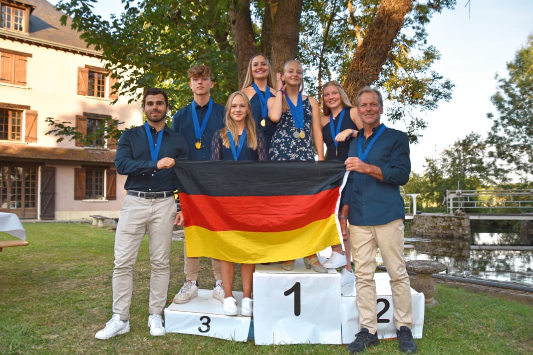 A flag with seven upright people, from left: Kenneth Eissler, Ben Zinn, Alessa Pieroth, Jacky Kirsch, Bonnie Zinn, Maja Mogge and Frank Zinn became Team Germany European Barefoot Champions in 2022