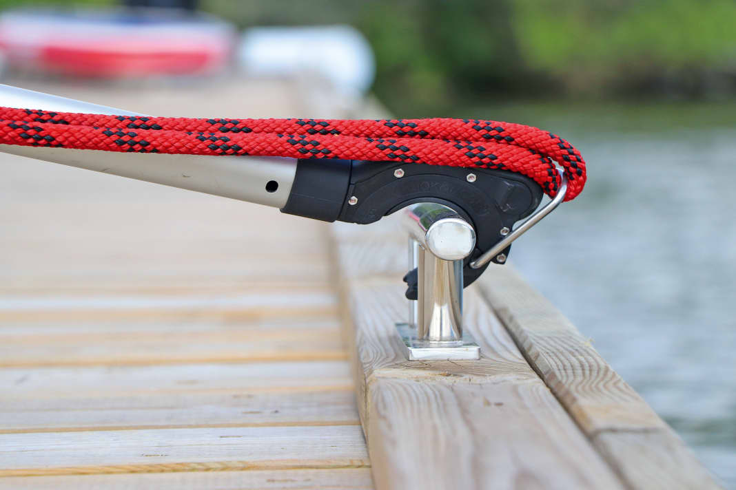 The spliced-in eye of the line is attached to a metal bracket. The hook is placed over the cleat and the mechanism is released by pulling on the boat hook