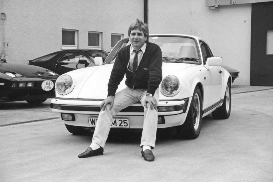 MANFRED WINKELHOCK startete sowohl in der Formel 1 als auch in der Sportwagen-Weltmeisterschaft. In der Formel 1 bestritt er 47 Rennen für Teams wie ATS, Brabham und RAM und holte zwei WM-Punkte. In der Sportwagen-WM siegte er mehrmals. Das Bild zeigt ihn im Sommer auf dem Werksgelände mit seinem neuen 911 Carrera 3.2, der im Januar 1985 gebaut wurde und 231 PS leistet