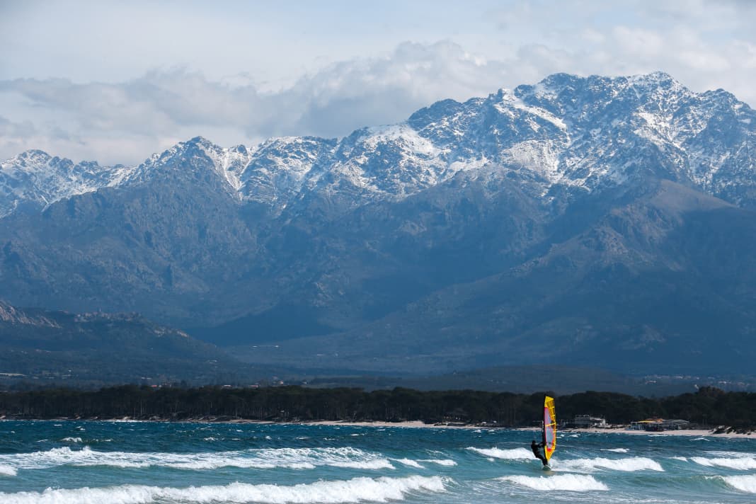In der Bucht von Calvi surft man mit Blick auf die imposante Kulisse Korsikas. Die Berge rund um den über 2700 Meter hohen Monte Cinto sind im Frühjahr oft noch vom Schnee bedeckt.