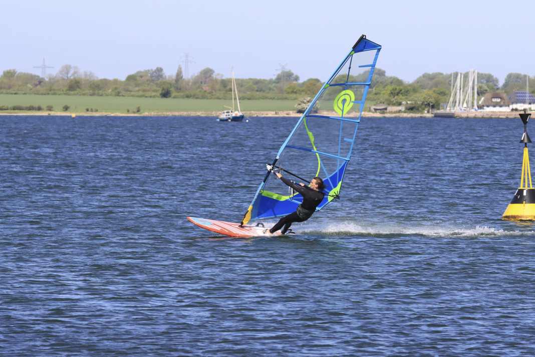 Pick up speed on a half-wind course and put your back foot out of the loop in preparation. Also unhook yourself from the harness. Start the turn to windward by applying slight pressure to the windward edge.