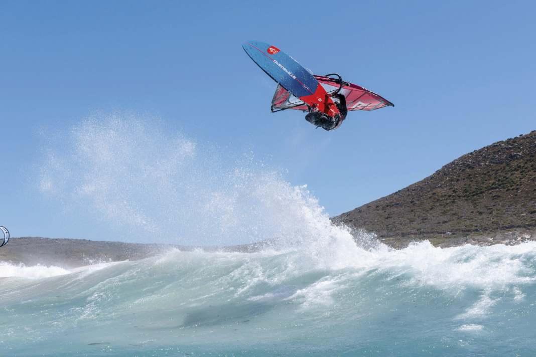 On a half-wind course, I head towards a medium-steep wave in a controlled manner. The sail is close to my body and my hands tend to grip the boom a little tighter, the front hand closer to the mast. A compact body position. One thing is particularly important here: no stress! You should first gain some height before you start kicking the board out. If you tense up during the initiation, you will lose time in the air. The jump comes from the legs. Afterwards, I try not to hang my body too much under the sail. Because the sail remains tight so that I can continue to climb