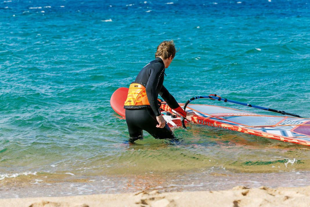 1 To start, set your board half-windward (crosswind) and grip the mast with your front hand directly above the boom.