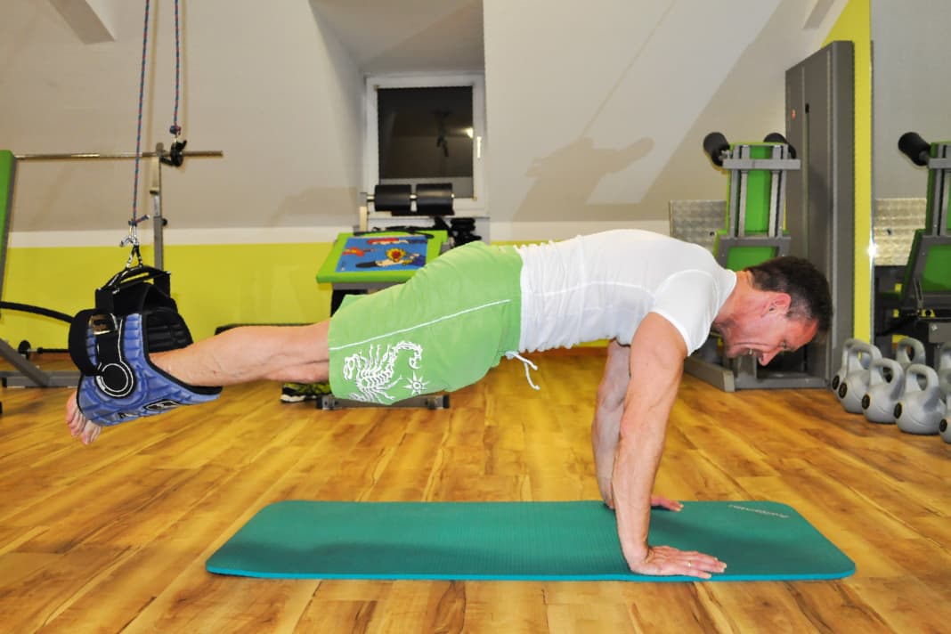 Get into a push-up position and hang your legs on the trapeze