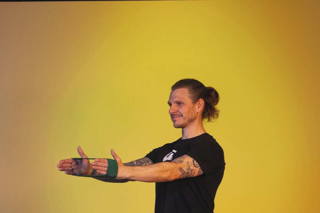 Place a loop band around your hands.  Tighten the band and move your hands as far apart as possible.  Now stretch your arms forwards and hold against the resistance exerted by the band on the back of your hands. Breathe out as you stretch.