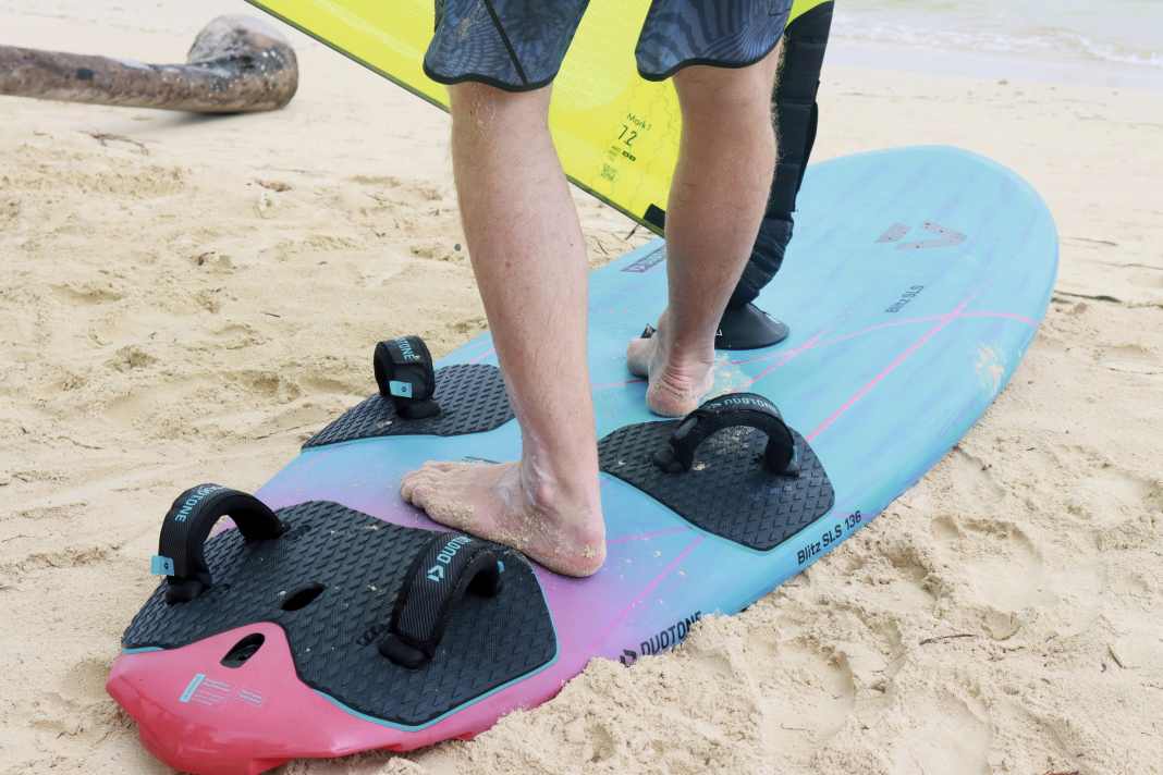 In die Schlaufen wechselst du, wenn das Board aus der Verdrängerfahrt ins Gleiten übergeht. Hier der ideale Ablauf: In der Angleitphase steht der hintere Fuß zwischen den Schlaufen an Deck. Der vordere Fuß befindet sich zwischen Mastfuß und den vorderen Straps. Das Nach-vorne-Drehen des Fußes bewirkt, dass der Schub in Fahrtrichtung aufs Board übertragen wird. Achte darauf, den vorderen Fuß nicht quer zur Fahrtrichtung zu stellen – das erhöht die Querkräfte!