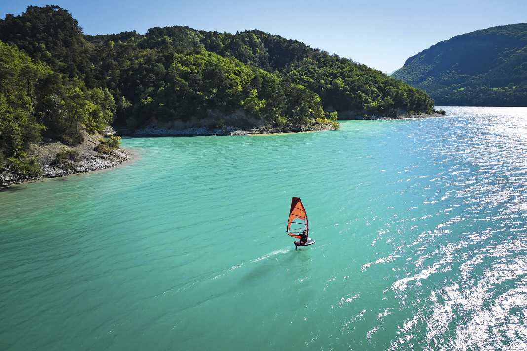Das Windsurf-Foilen hat nicht nur den Einsatzbereich der Boards enorm erweitert, sondern auch Reviere interessant gemacht, die dem klassischen Windsurfer vielleicht zu langweilig erschienen. Viele Seen in Deutschland oder wie hier der Lac Monteynard in den französischen Alpen haben plötzlich wieder ihren Reiz.