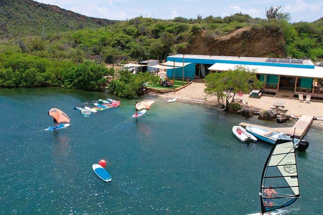 Durch die Tiefe auch sehr schön zum Foilen: Karibik-Feeling mit entspanntem Surf-Vibe machen bei Windsurfing Curaçao den böigen Wind wieder wett.