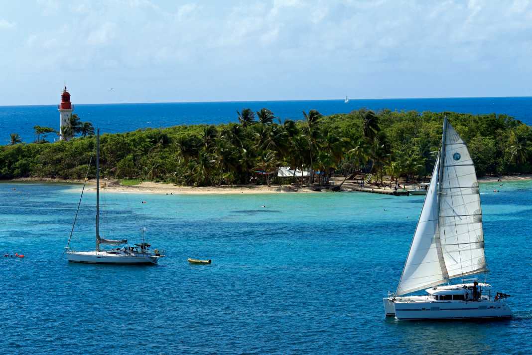 Ein Kat segelt vor der kleinen Insel Le Gosier direkt an der Südküste Guadeloupes. Der Ankerplatz vor dem palmenumsäumten Leuchtturm ist perfekt für den ersten oder letzten Törntag.