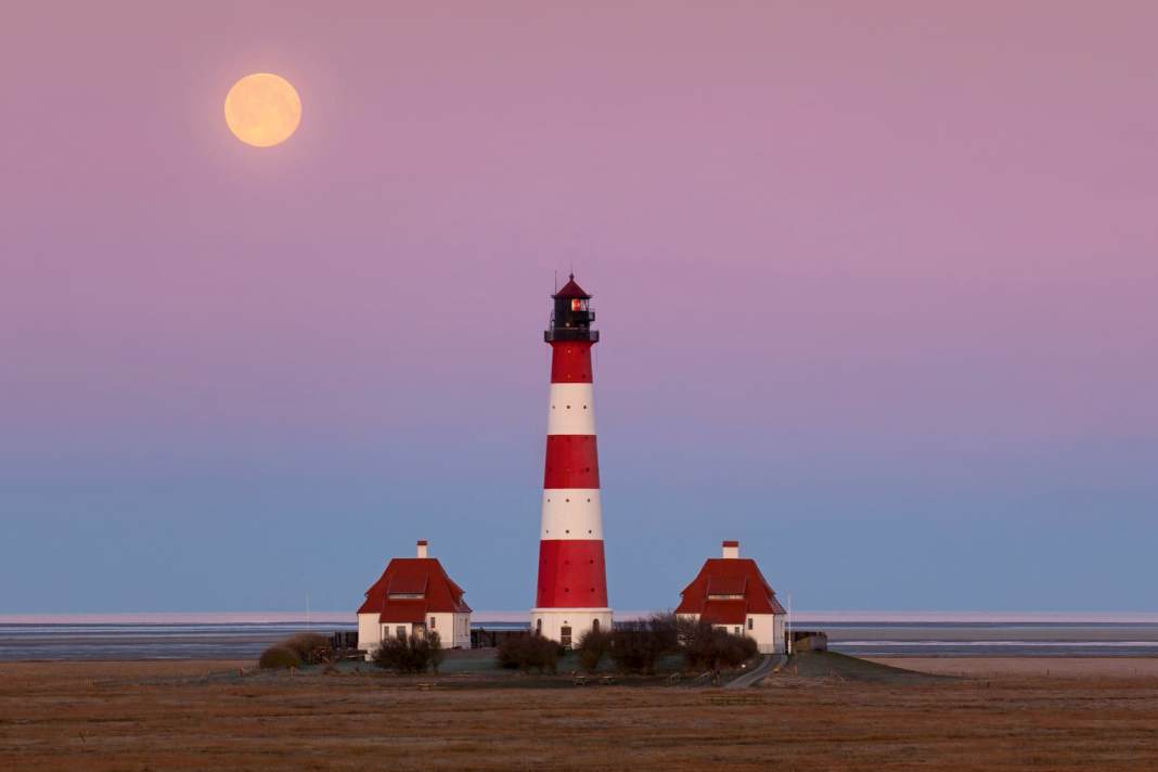 Il faro di Westerheversand sulla penisola di Eiderstedt. Con le sue due caratteristiche casette dei guardiani, questo gigante a strisce bianche e rosse dello Schleswig-Holstein è un soggetto pubblicitario molto utilizzato e, per questo motivo, forse il faro più famoso della Germania. | alimdi/Arterra