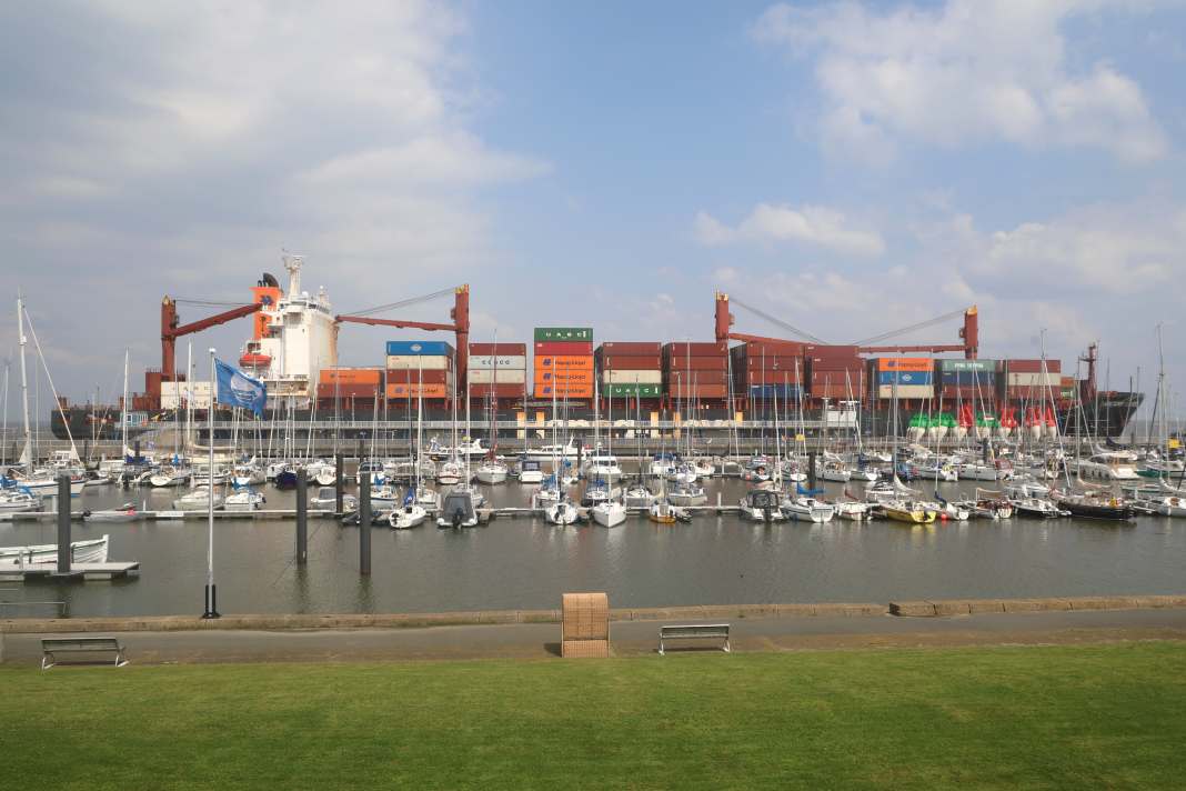 Un haut mur de quai sépare les pontons de l'association de l'Elbe, à droite sur la photo l'entrée du port. Dehors, un porte-conteneurs vient de s'amarrer.