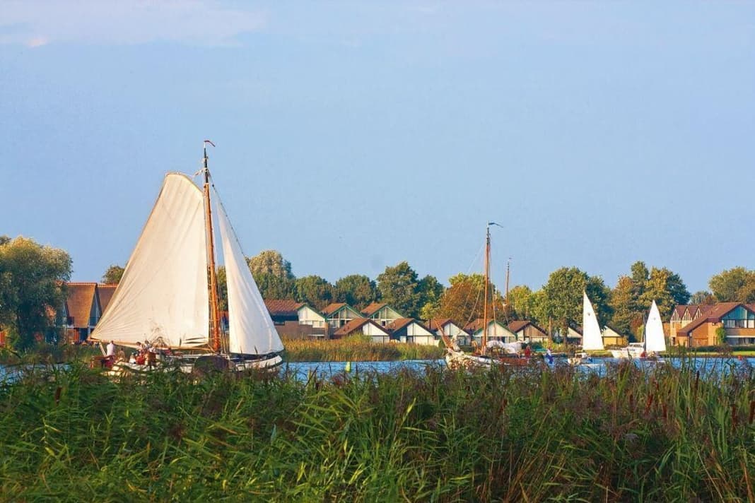 A flat-bottomed ship sails off the town of Heeg