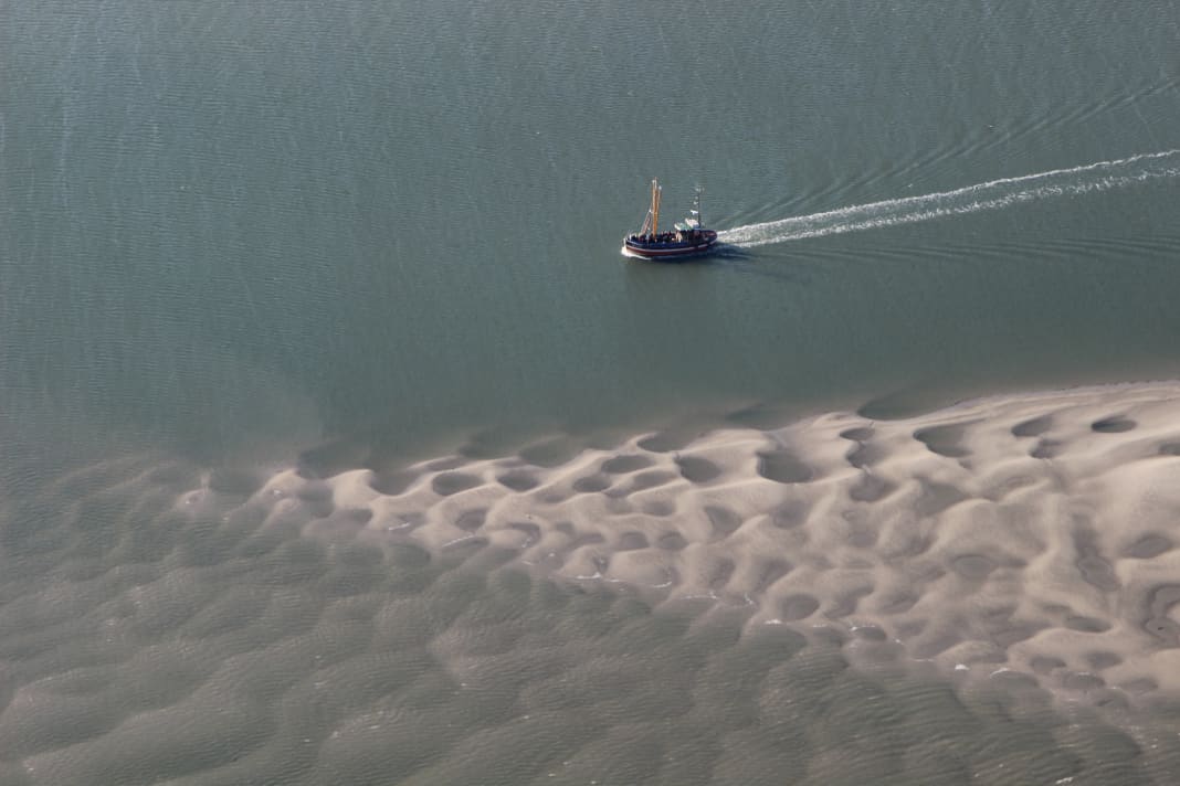 Ein einsamer Kutter passiert eine Sandbank bei Langeoog