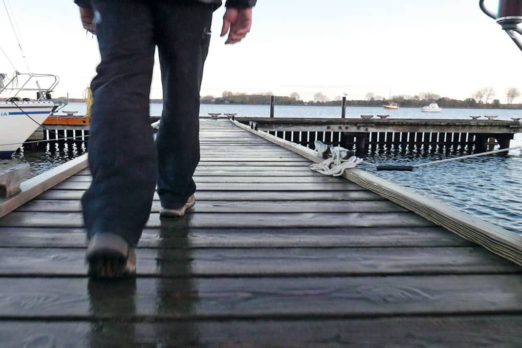 The protagonist walks across the footbridge, only his feet are visible