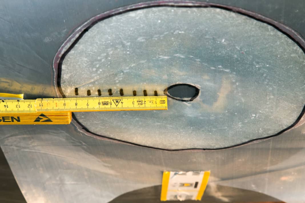 Sand the stock: Sand a stock twelve times the thickness of the laminate around the hole, in this case about ten centimetres. Transfer the outline to a sheet of foil and mark the size of the fibreglass patches on it.