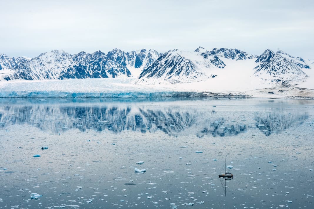 The 66-foot aluminium yacht "Qilak" in the ice field in front of the snow-covered mountains and one of the glaciers on the west coast of Spitsbergen