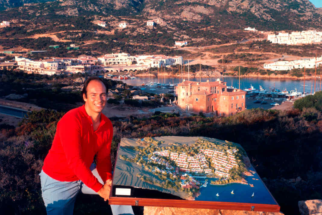 Le prince Karim Aga Khan en 1960 sur une colline au-dessus de Porto Cervo, avec en arrière-plan le Yacht Club Costa Smeralda qu'il a cofondé.