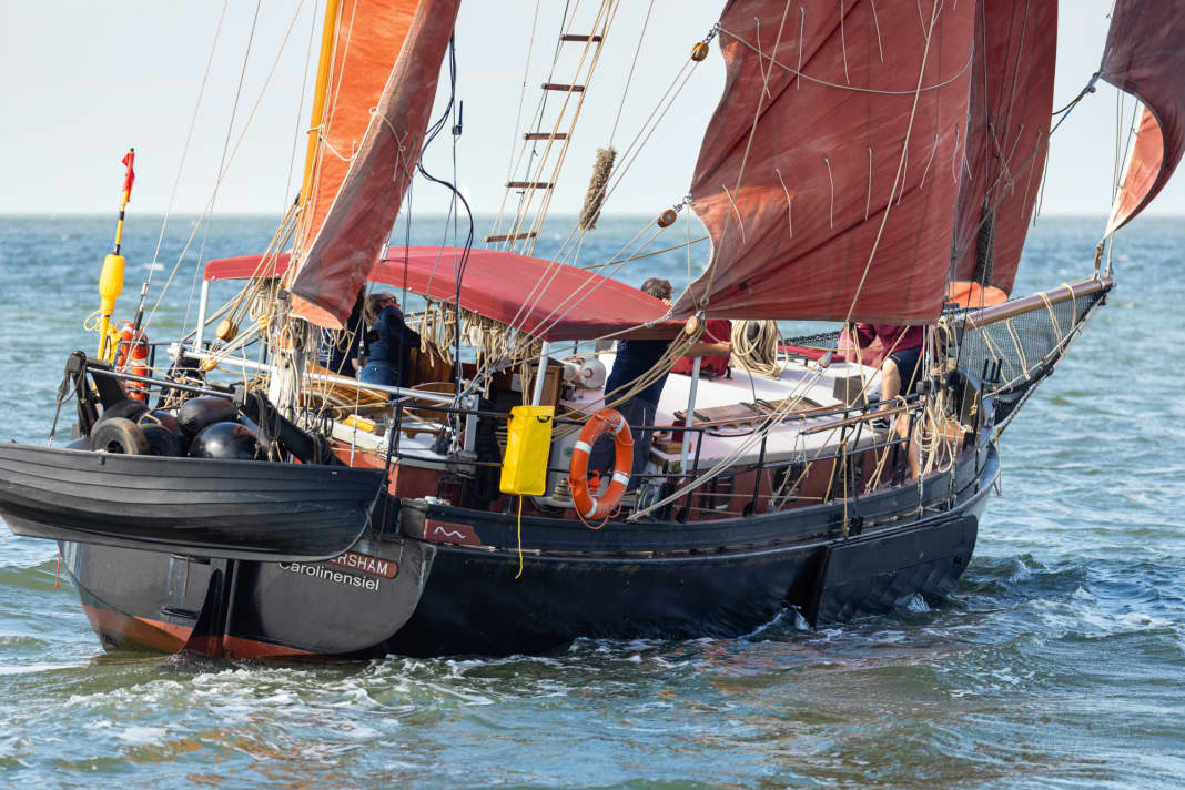 Rote Segel über einem schwarzen Rumpf erinnern an ein Arbeitsboot. Die Seitenschwerter liefern Auftrieb, der Innenballast Stabilität