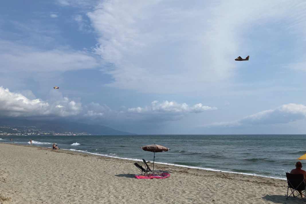In molte località del sud della Francia, come qui su una spiaggia a sud di Bastia, in Corsica, sono attualmente in azione aerei antincendio per domare i devastanti incendi boschivi.