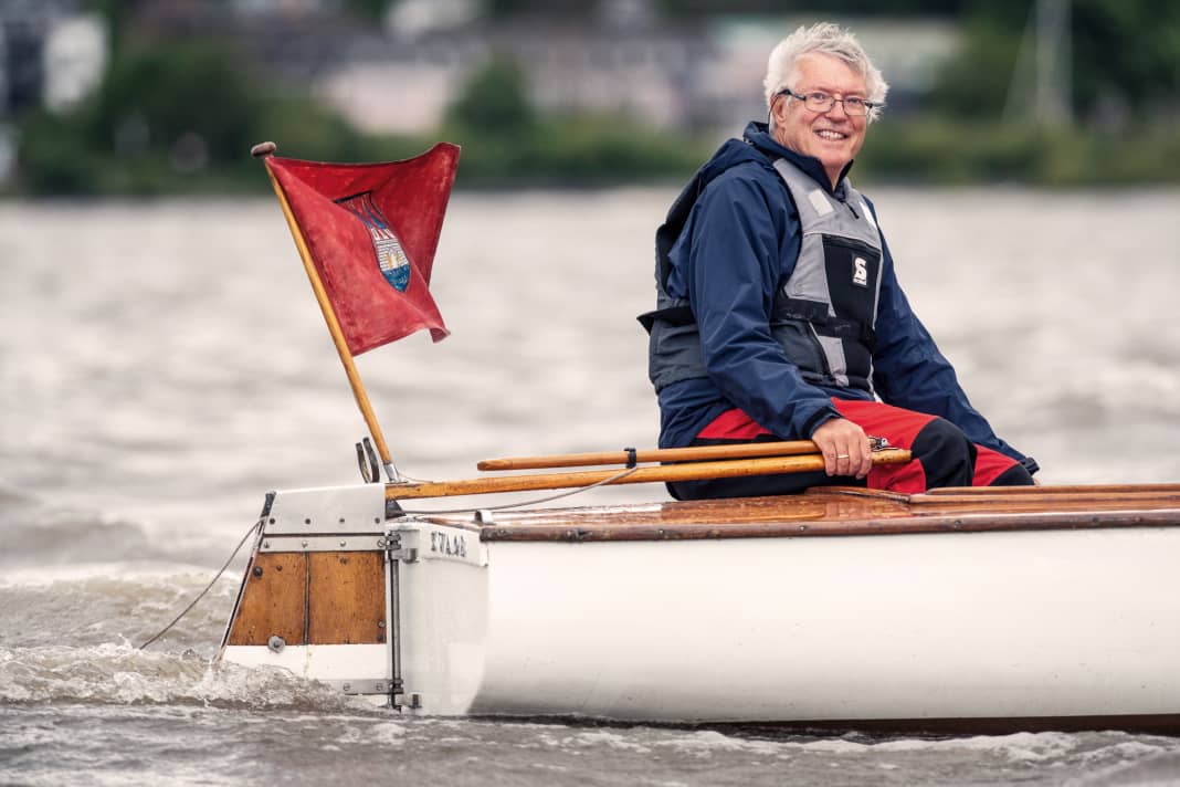 Con la bandiera della città di Altona a poppa e la barra del suo "Woge" centenario in mano, il presidente del dinghy si sente a casa.