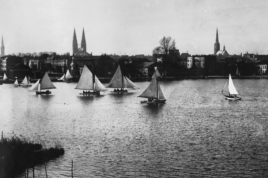 Segler des Lübecker Yacht-Clubs mit ihren Booten auf  der Wakenitz, im Hintergrund die Kirchtürme Lübecks