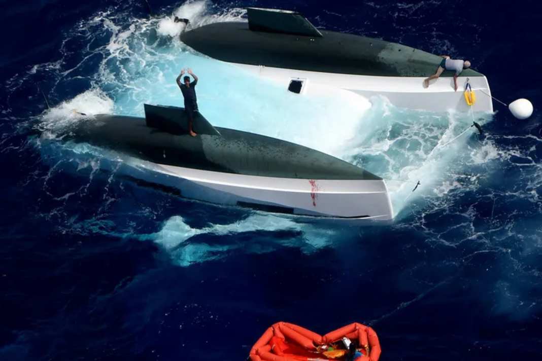 Image prise dans le Falcon 50 : un membre d'équipage sur le fuselage bâbord fait signe, un deuxième est couché sur la proue tribord.