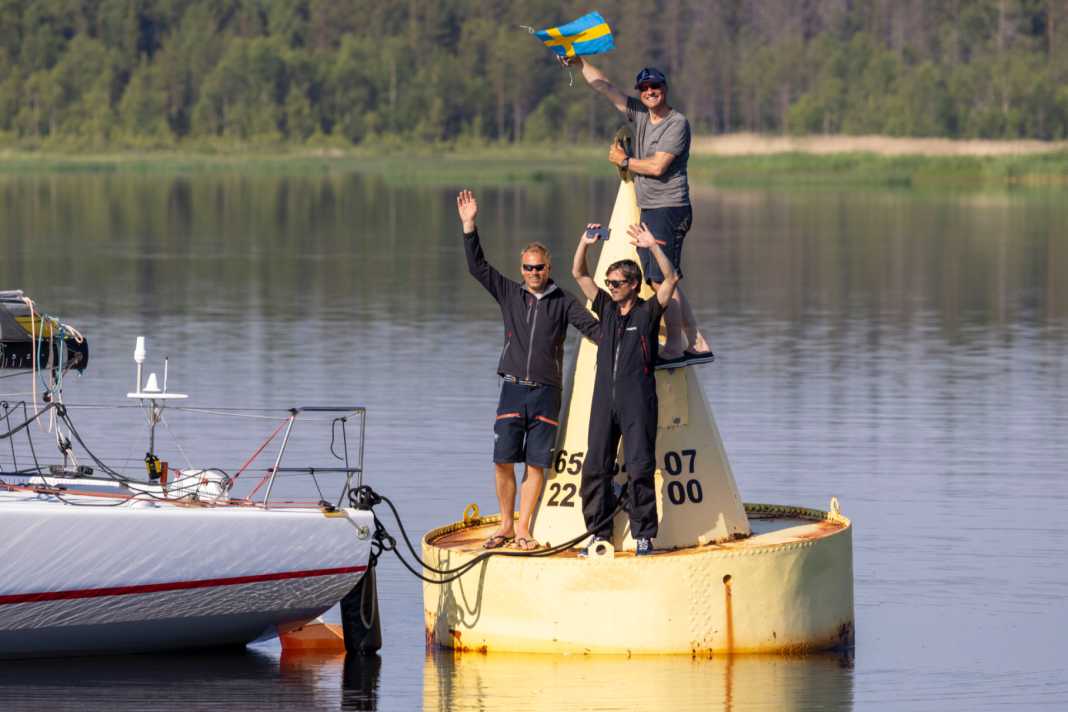 L'équipage du record "Red" autour du skipper Mathias Müller von Blumencron (avec le drapeau) après son succès en juin 2022 sur la légendaire bouée d'arrivée jaune de MidsummerSail.