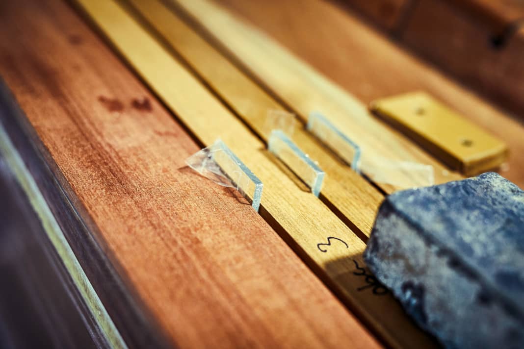 Il est préférable de coller les baguettes de teck sur toute la surface du contreplaqué. Le poids du plomb assure une pression régulière.