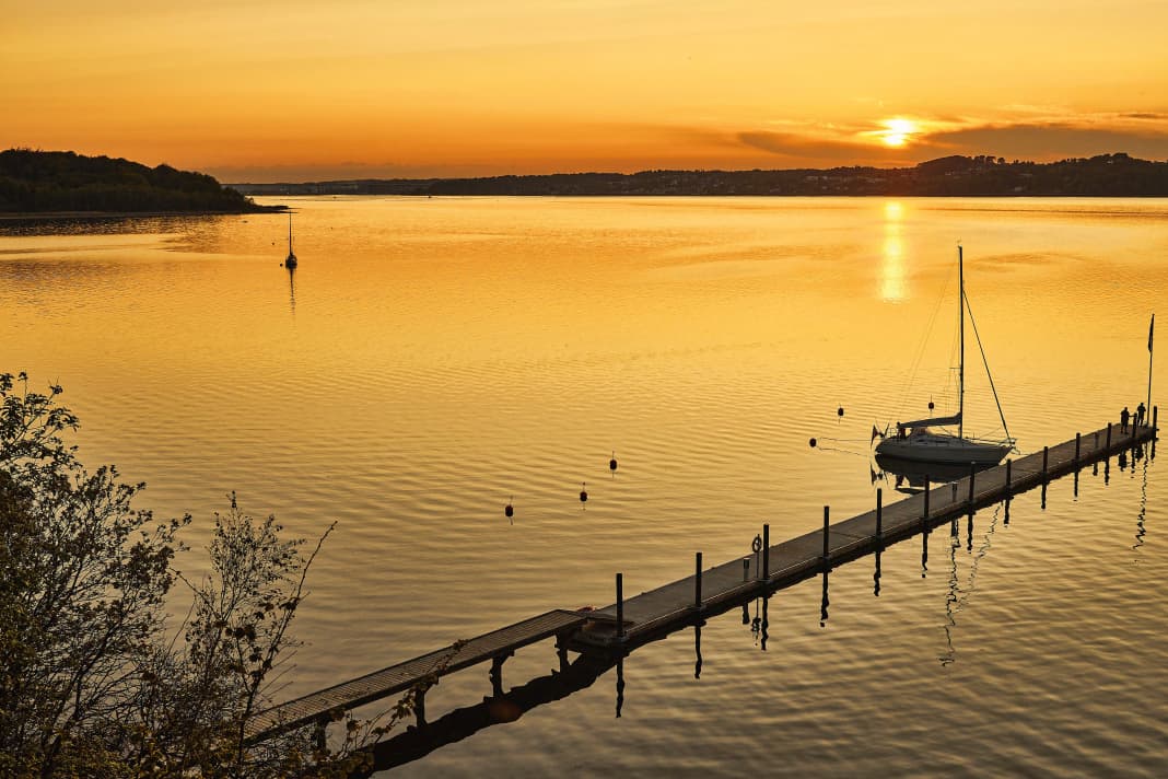 Goldener Moment. Einsam liegt eine Yacht am Steg in der Andkær Vik am Südufer des Vejle-Fjords. Lediglich ein weiteres Boot hat an einer der Muringbojen festgemacht
