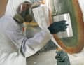 Adhesive: Precisely dosed and well mixed, an adhesive resin is applied to the old mirror plate cut-out using a wide spatula