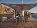 A mobile bimini casts shade over the dining area on deck.
