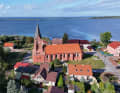 Vue de l'église de Nowe Warpno avec la lagune derrière elle.