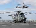 Sea King helicopter stands on the flight deck of the Dutch dock landing ship HNLMS Rotterdam and an NH-90 NTH Sea Lion (right) flies past during the military evacuation exercise Schneller Adler 2022 in the Kiel Fjord on 3 May 2022.