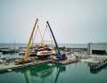 Two cranes lift the 28-metre cat into the water.