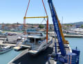 Two cranes lift the yacht.
