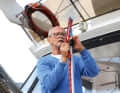 The eye of the line is placed over the tip of the boat hook and inserted into the Sailmatic clamp with the lower end of the eye