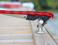 The spliced-in eye of the line is attached to a metal bracket. The hook is placed over the cleat and the mechanism is released by pulling on the boat hook