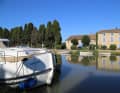 Die Pénichette Neo von Riverly vor der malerischen Kulisse von Le Somail am Canal du Midi.