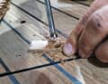 Um die Schrauben tiefer ins Holz zu bekommen, werden die Löcher nachgebohrt. Eine Schablone mit passendem Loch führt den Forstnerbohrer von außen, denn seine Zentrierspitze fasst in der alten Bohrung nicht