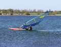 Of course, you should quickly reach round the mast with your front hand. The aim of this is to bring the sail into a more upright position so that it can catch more wind. As soon as you’ve reached round, you’ll feel the extra lift from the sail.