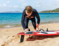 Lay the board with the tail facing the wind and, if possible, press the fin into the sand