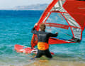 Now you want the sail over your head without the boom end getting stuck in the water. Therefore, pull the mast forwards over your head with your front hand.