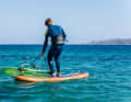 To get started, the board must first be turned into the correct position. To do this, stand on the board with your feet immediately to the left and right of the foot of the mast and grab the furling line far down.
