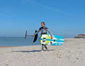 Wie immer gilt: Zuerst das Brett, da dir dieses am Strand nicht so schnell wegfliegen kann. Greife mit einer Hand die vordere Schlaufe des Boards, die andere Hand greift an der Fuselage. Der Vorteil dieser Technik ist, dass du das Foil beim Laufen immer sehen kannst.