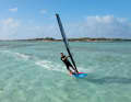 1) The foot change for the duck tack takes place before you duck. To ensure this is successful, ease off the sail slightly and, on a light broad reach, switch your feet by first moving your front foot back (heel-to-heel) and then immediately moving your back foot forward towards the mast foot. You can initiate the duck tack from a half-planing or full-planing position on a half-wind course. After a successful foot change, luff slightly again.