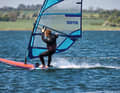 2. Der Schritt in die Schlaufe: Viele, die das Schlaufensurfen lernen wollen, wechseln zu früh in die Strap und würgen das Angleiten damit ab. Daher gilt: Erst wenn du eine stabile Gleitfahrt erreicht hast, setzt du den vorderen Fuß in die Schlaufe. Häufiges Problem: In dem Moment, wo der vordere Fuß angehoben wird, liegt es nahe, das komplette Körpergewicht auf den hinteren Fuß zu verlagern. Dieses Problem umgehst du über die richtige Trapeztechnik und eine spezielle Körperhaltung. Mit hoher Gabel und längeren Tampen kannst du Gewicht über das Trapez und die Gabel auf den Mastfuß bringen. Hänge dein Körpergewicht in dieser Phase bewusst ins Trapez und neige den Oberkörper leicht nach vorne, so als wolltest du am Mast vorbei auf die Leeseite blicken. Dein Körpergewicht lastet nun im Prinzip auf „drei Beinen“ – Mast, vorderer Fuß &amp; hinterer Fuß. In der Folge kannst du nun das „mittlere“ (= dein vorderes Bein) anheben und den Fuß in die Schlaufe setzen, ohne dass du das Heck übermäßig stark belasten musst.