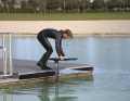 Man startet vom Steg aus gebückter Position. Brett und Foil befinden sich in Fahrtposition neben dem Steg. Die Hände halten das Board an den Rails fest. Die eine Hand stabilisiert das Board weiter vorne und die andere näher am Heck. So bleibt das Brett austariert, um es beim Anlaufen sauber neben dem Steg herführen zu können. Der Frontflügel sollte sich dabei nur wenige Zentimeter unter der Wasseroberfläche befinden.
