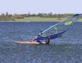First, place your front hand on the mast, then your back hand on the lower leech.